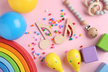 Baby song concept. Wooden notes, kids maracas and toys on pink background, flat lay