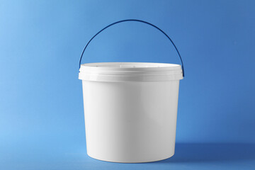 One plastic bucket with lid on light blue background - obrazy, fototapety, plakaty