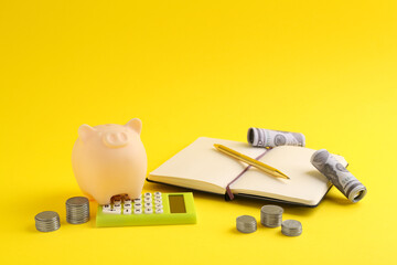 Financial savings. Piggy bank, money, calculator and stationery on yellow background