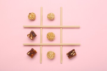 Tic tac toe game made with sweets on pink background, top view