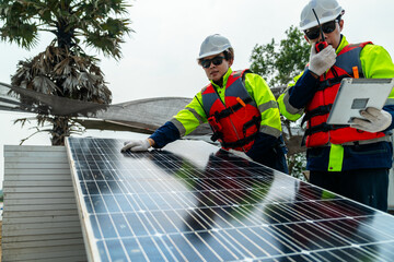 engineer men inspect modules of photovoltaic cell panels. Industrial Renewable energy of green power. workers prepare materials before construction on site with the stack of panels at background.