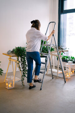 girl florist hangs a flower arrangement from the ceiling 
