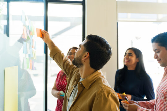 Hispanic businessman using sticky notes and collaborating with his team in an office