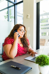 Fat businesswoman in casual clothing talking to a client on her smartphone and looking at her...