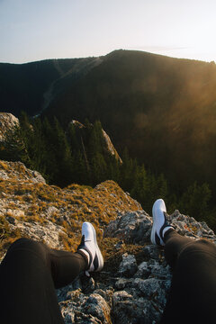 A man sitting on the cliff edge, Photo of legs dangling over the edge