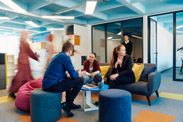 Obraz premium Multiethnic startup business team on meeting in a modern bright open space coworking office. Brainstorming, working on laptop. Group of coworkers walking around in motion blur