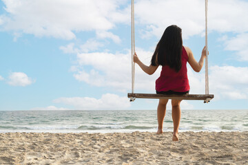 Traveler woman relaxing on swing with sea beach, summer holiday vacation trip.