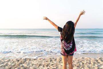 Summer beach vacation concept, happy woman raising hands up on sea beach background.