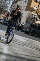A joyful young man rides a bicycle through urban streets while listening to music on his headphones...
