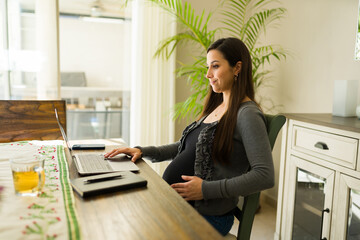 Beautiful busy pregnant woman working from home
