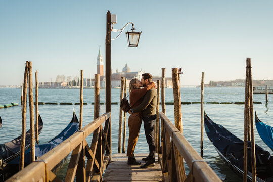 Happy couple kissing near gondolas in Venice - Powered by Adobe