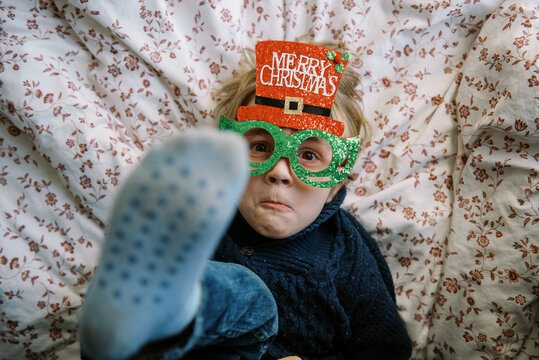 smiling toddler in blue knit sweater with christmas glasses