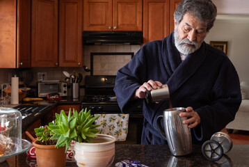 Retired latin man using a french press making coffee in his kitchen