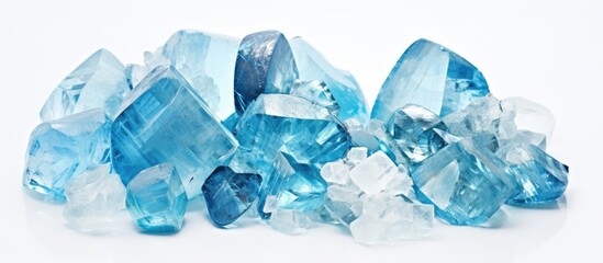A close-up view of a collection of rare blue crystals piled neatly on top of a pristine white table. The crystals sparkle under the light, showcasing their unique aquamarine texture and color.
