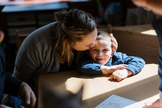 mother and toddler son cuddling together in booth at table