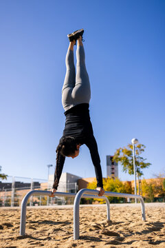Fit sportswoman doing handstand on parallel bars during workout
