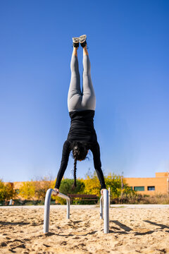 Fit athlete performing handstand on parallel bars during workout