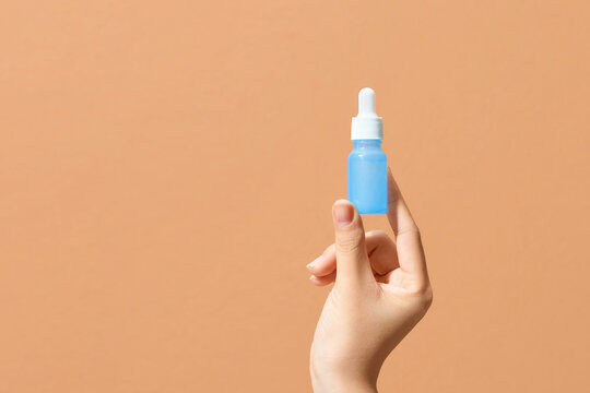 Hand holding a medical glass dropper bottle