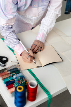 Crop woman writing in notepad. Small business concept. Seamstress.