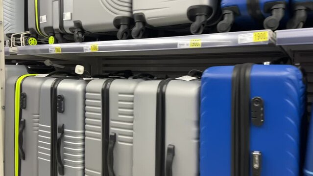 Variety of polycarbonate suitcases on a store shelves. The suitcases are of different sizes, colors, styles. They are made from durable, lightweight, and scratch-resistant polycarbonate material