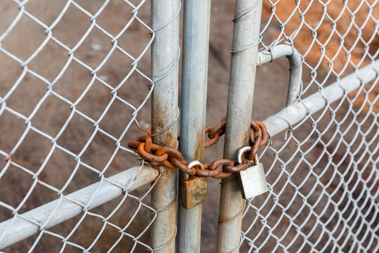 Locks and Chains on Metal Fence Connecting to Gate