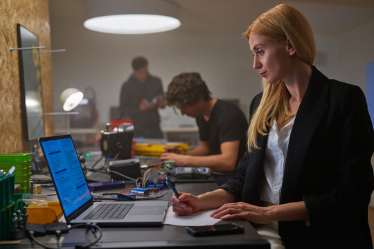 A businesswoman taking notes while watching a presentation online