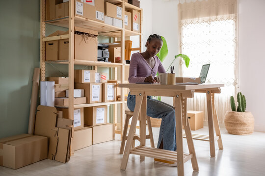 Black logistic manager writing notes at table
