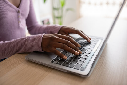 Black female freelancer typing text on laptop