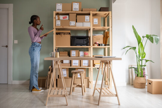 Busy female manager checking carton boxes on shelves