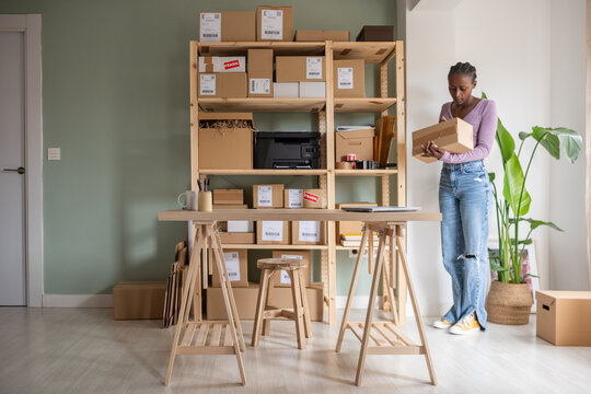 Busy female manager checking carton boxes near shelves