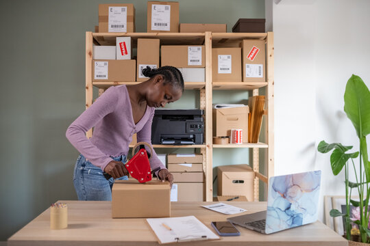 Black woman attaching adhesive tape to box