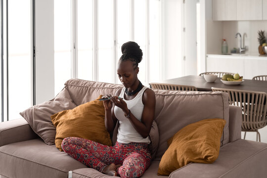 Black woman filing nails on sofa