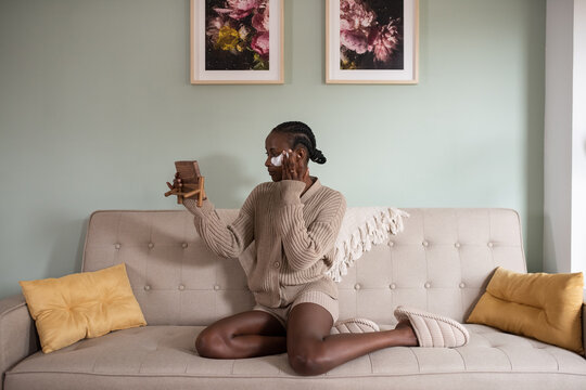 Black woman applying eye patch in morning