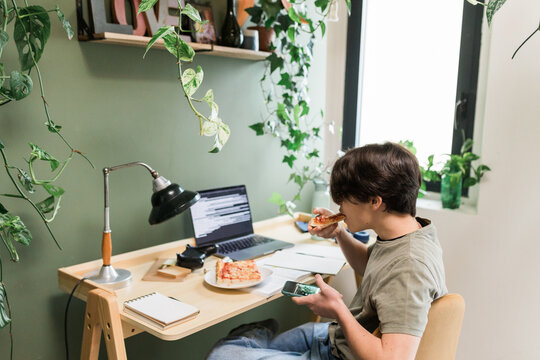 Teen Boy Student Eating Pizza Near Laptop