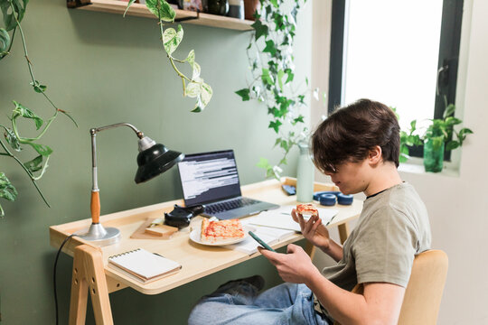Teen Boy Student Eating Pizza Near Laptop