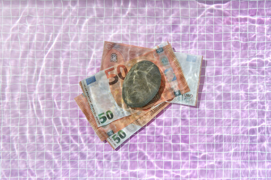 100 euro bills pressed by stone at the bottom of pool.