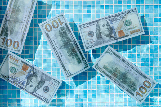 Clear pool water with floating 100 dollar banknotes.