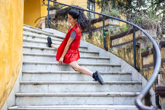Curly hair acrobat doing splits and dancing on stairs at park
