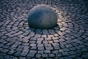 A stone orb embedded into the circular arrangement of stones in the pavement.