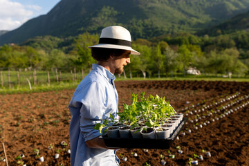 man holding two trays with seedlings