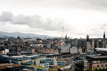 Dense panoply of buildings stretching down to horizon with a cloudy sky in the background.