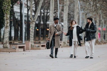 A group of young, enthusiastic business entrepreneurs engage in a lively discussion while walking through a city park, embodying the spirit of modern remote working and collaboration.