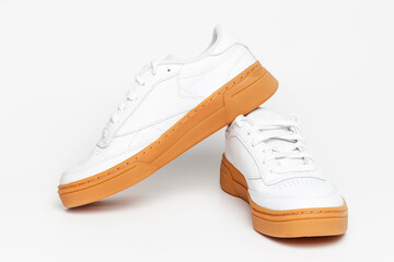 White sneaker with brown sole on white background close-up.
