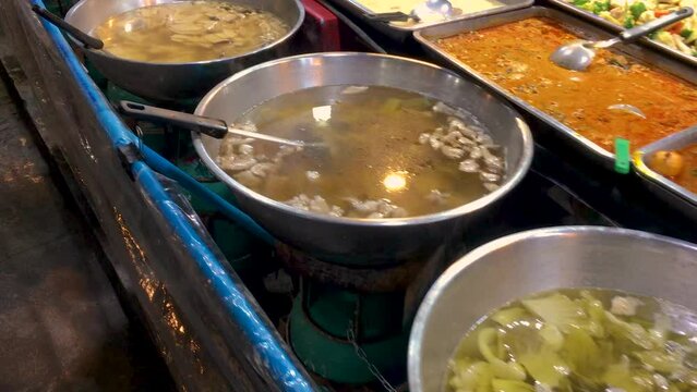 March 5, 2022. Thepprasit Night Market, Pattaya Thailand. Curries, soups and other wet Thai cuisine in metal serving dishes on a vendors table.