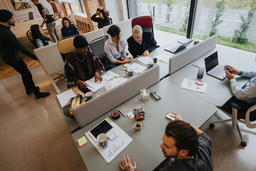 A multicultural group of professionals collaborates in a well-lit office setting, brainstorming...