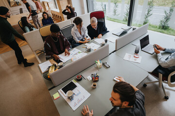 A multicultural group of professionals collaborates in a well-lit office setting, brainstorming ideas and strategizing with enthusiasm.