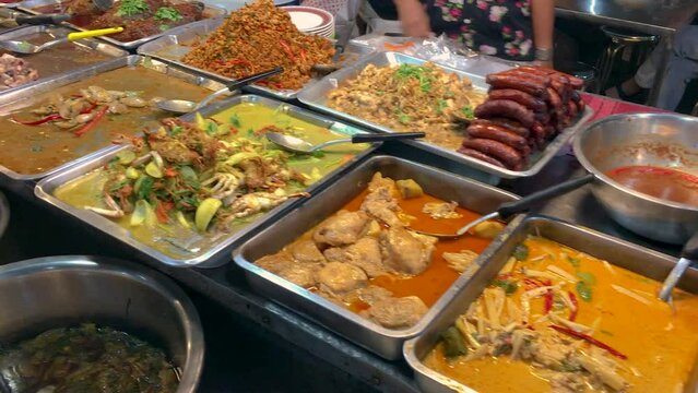 March 5, 2022. Thepprasit Night Market, Pattaya Thailand. Curries, soups and other wet Thai cuisine in metal serving dishes on a vendors table.