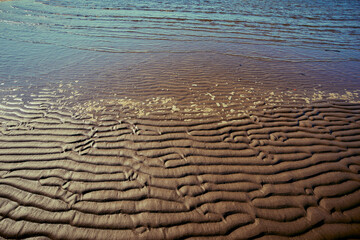 Sea shore exposing sandbank with patterns that water left in the wake of low tide.