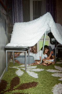 Teenager with a textbook on a carpet with an electric torch. 