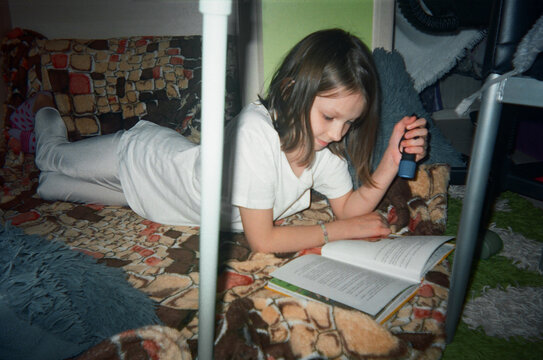 Teenager with a textbook on a carpet with an electric torch. 